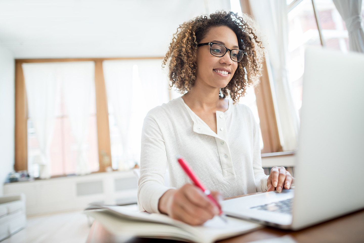 woman looking at laptop and making notes